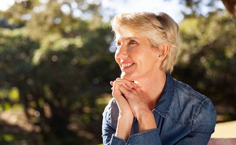 A smiling middle-aged woman represents the full life that can be led after thyroid cancer treatment.
