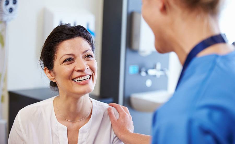 A smiling middle-aged woman talks to her doctor, representing the expert and compassionate thyroid disease treatment at Scripps.