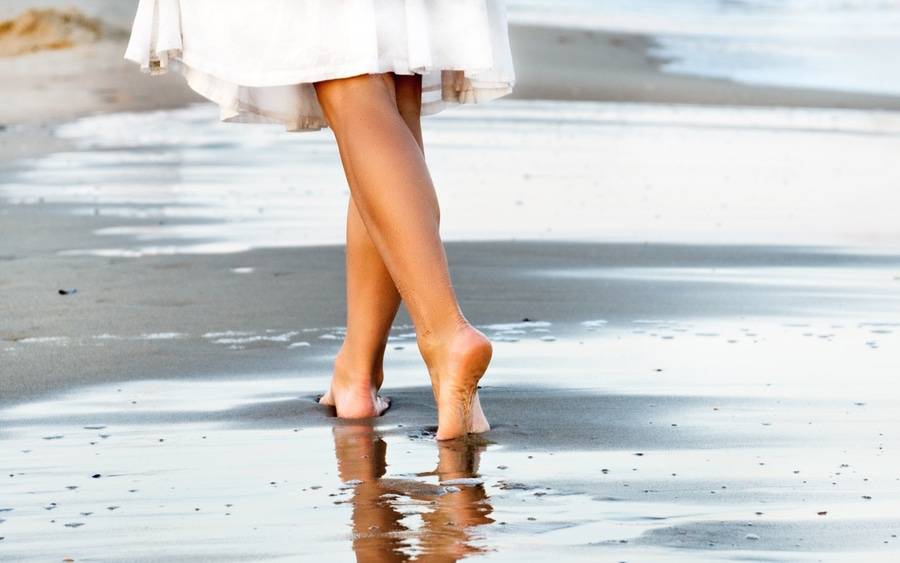 Woman walking on beach featured in article about varicose veins.