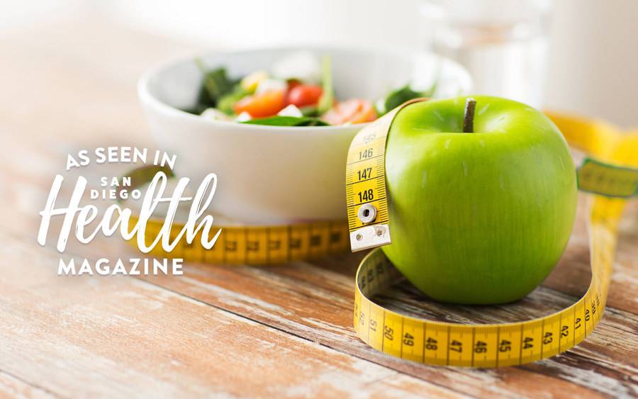 A healthy bowl of veggies, an apple and a measuring tape are featured in article about weight loss strategies.