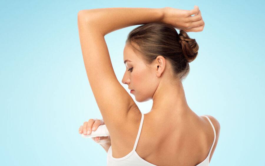 A woman applies a natural deodorant, which does not include aluminum.