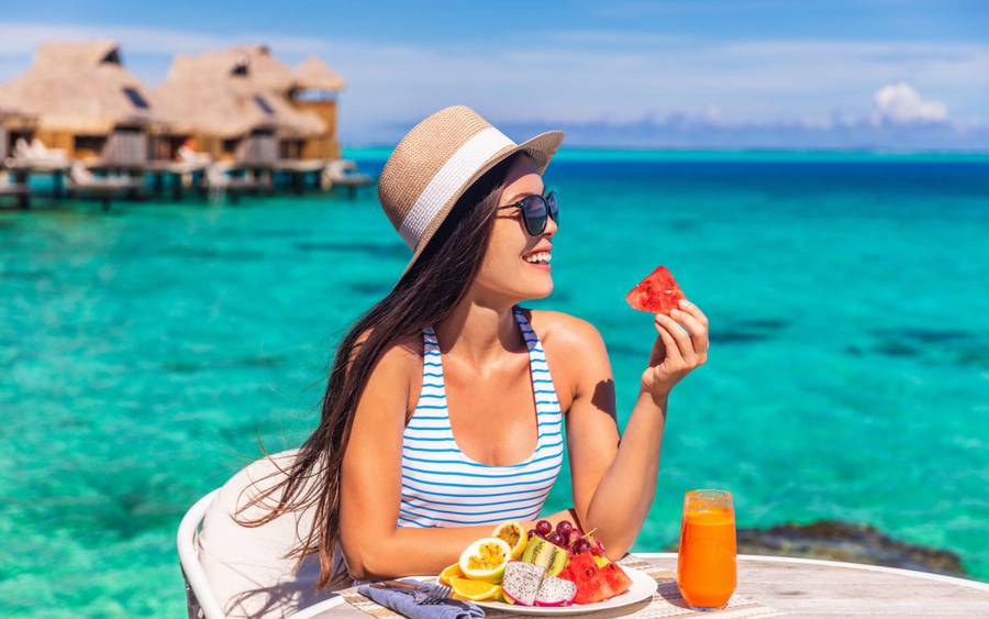 A woman eats a healthy watermelon during her vacation abroad.