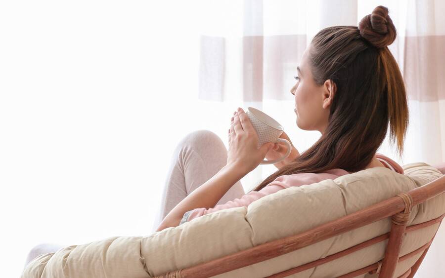 Stressed woman trying to relax on her couch with tea.