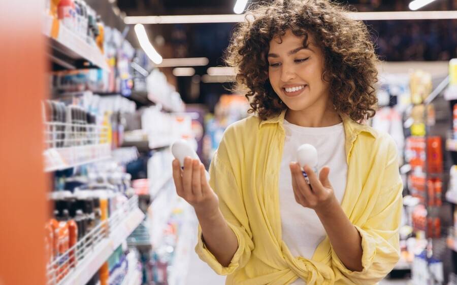 A young woman at the store shopping for an aluminum free deodorant but also considering an antiperspirant.
