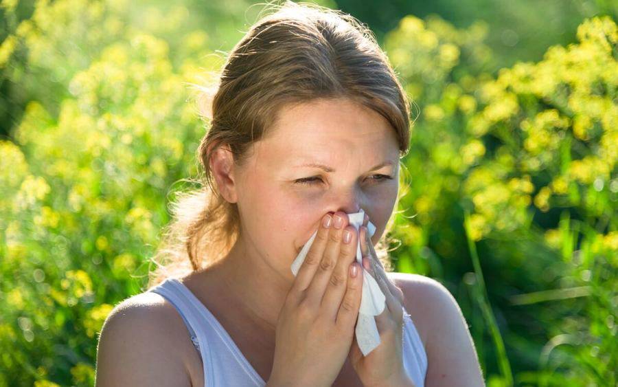 Woman sneezes due to allergies.