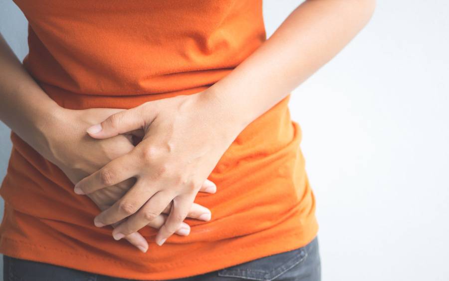 A woman grabs her stomach, experiencing digestive problems.