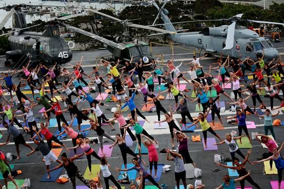 A group practicing yoga on the deck of an aircraft carrier in San Diego Harbor. 