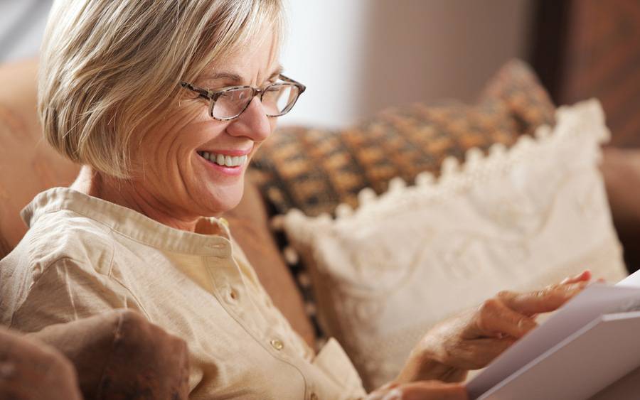 Older woman with presbyopia wears reading glasses to correct her poor vision.
