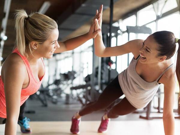 Two young women stretch and enjoy working out together.
