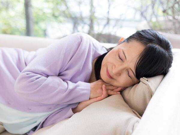 A woman stays home from work, opting to rest on the couch at home.