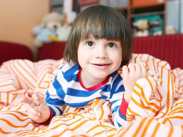 Smiling child in striped pajamas gets ready for bed. 