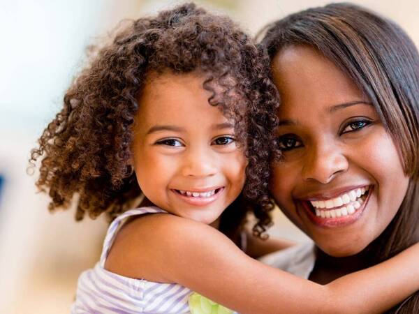 A smiling mother and daughter share a hug in the spirit of reducing stress for busy moms. 