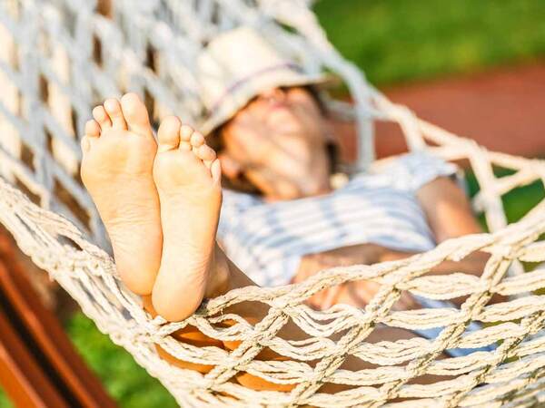 A young Caucasian woman in a hammock represents how a sedentary lifestyle can end up hurting your health.