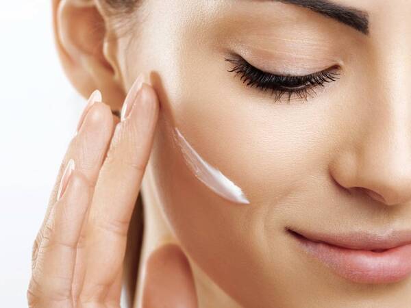 A woman appies moisturizer to her face for a healthy skin look. 