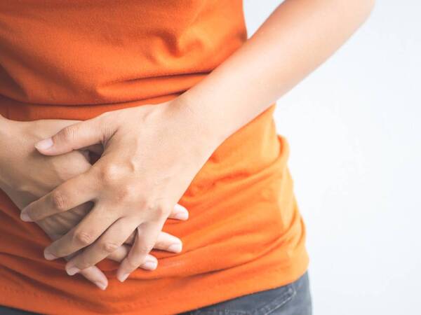 A woman presses her hands against her lower abdomen, showing how urinary tract infections and interstitial cystitis can cause pain and other bladder problems. 