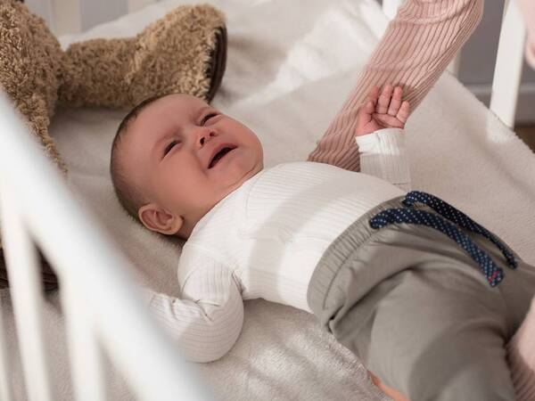 An infant with colic cries in his crib.