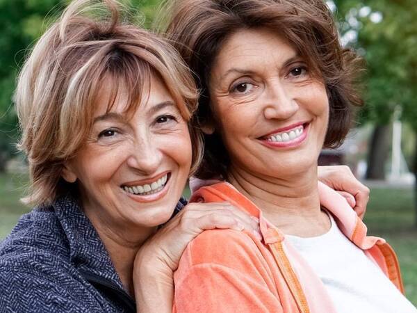 Two middle-aged women smile while enjoying some time outdoors.