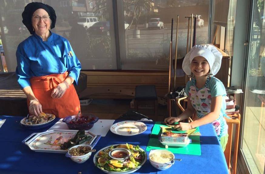 Scripps Mercy Hospital Executive Chef, Cynthia Qunionez prepares a plate of food with a young girl assisting her.