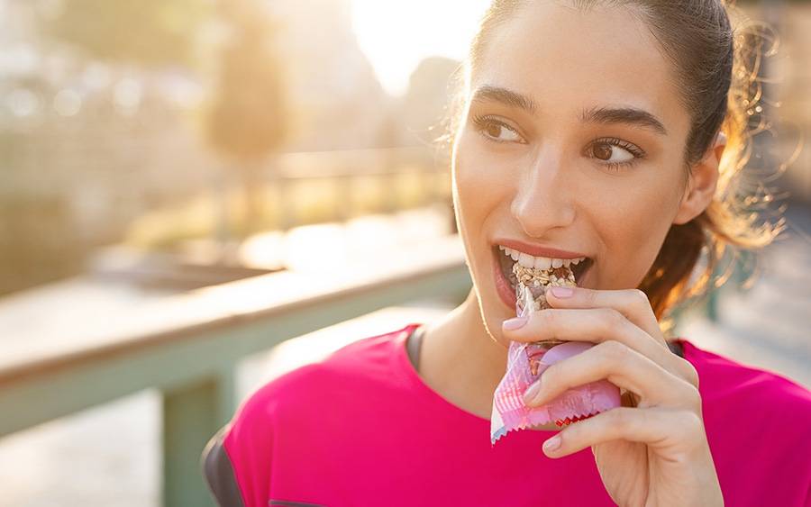 A young woman snacks on a chocolate grain bar.