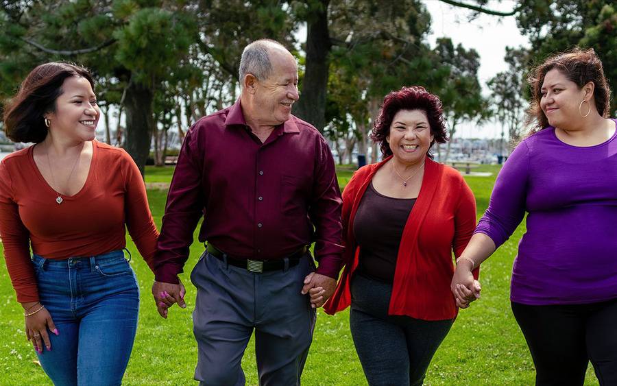 Edith Rodriquez wears a red cardigan and walks hand-in-hand with her family as she celebrates ovarian cancer remission.
