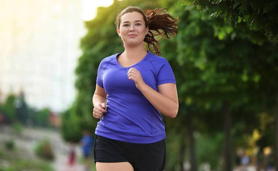 A woman runs in a park, representing a healthy lifestyle after weight loss surgery.