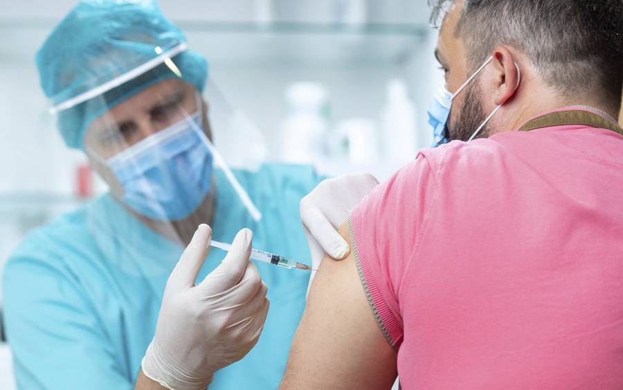 A man receiving his annual flu shot at a clinic whil wearing a mask