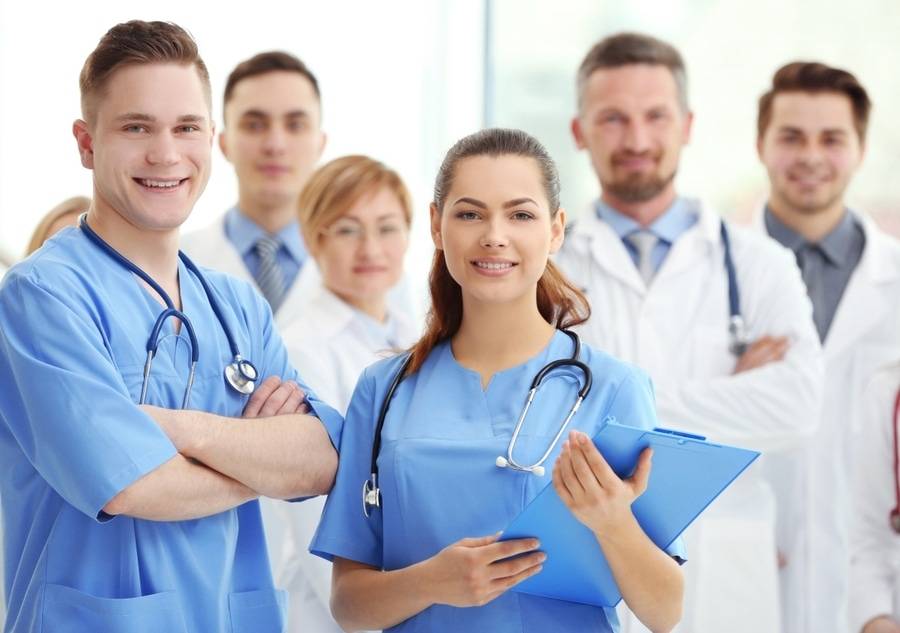 A group of doctors stand proudly and smile in a hospital.