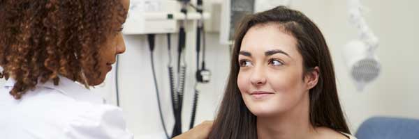 A doctor works with a female patient to diagnose cardiac arrhythmia.