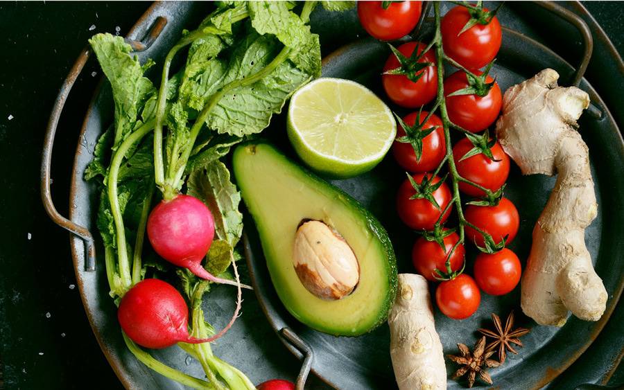 A sliced avocado is featured in a plate of healthy foods. Avocados are high on good fat.