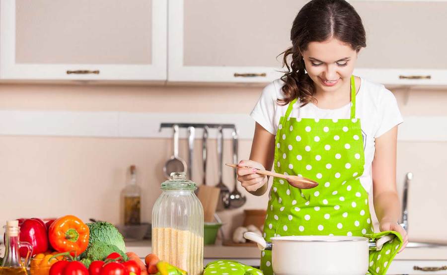 A woman prepares fresh produce and healthy grains in a kitchen, focusing on recipes designed for cancer patients.