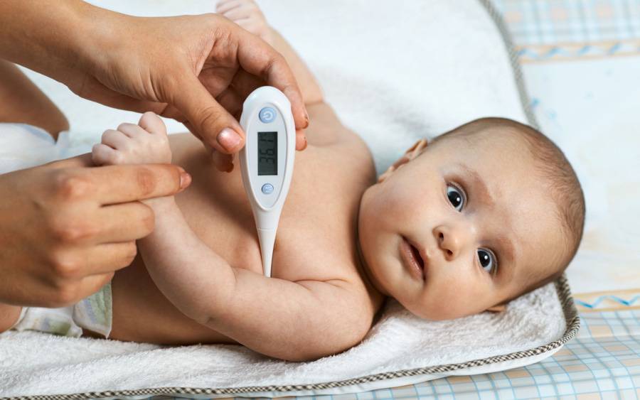 A baby with fever gets temperature taken with thermometer.
