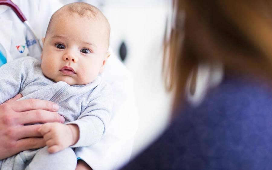 A mother looks on at baby held by Scripps HealthExpress Rancho Bernardo provider.