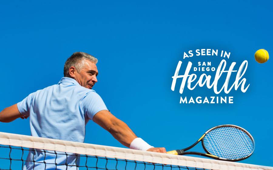 A man with gray hair is back on the tennis court as he hits a tennis ball after shoulder surgery using a new minimally invasive procedure fixes torn rotator cuffs - SD Health Magazine