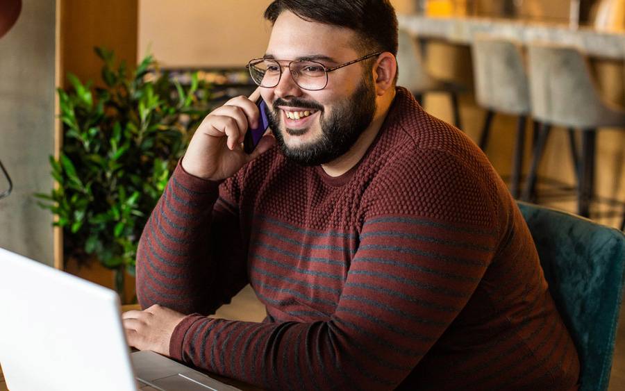 A young man listens to a call with his laptop open, representing a webinar on bariatric surgery.