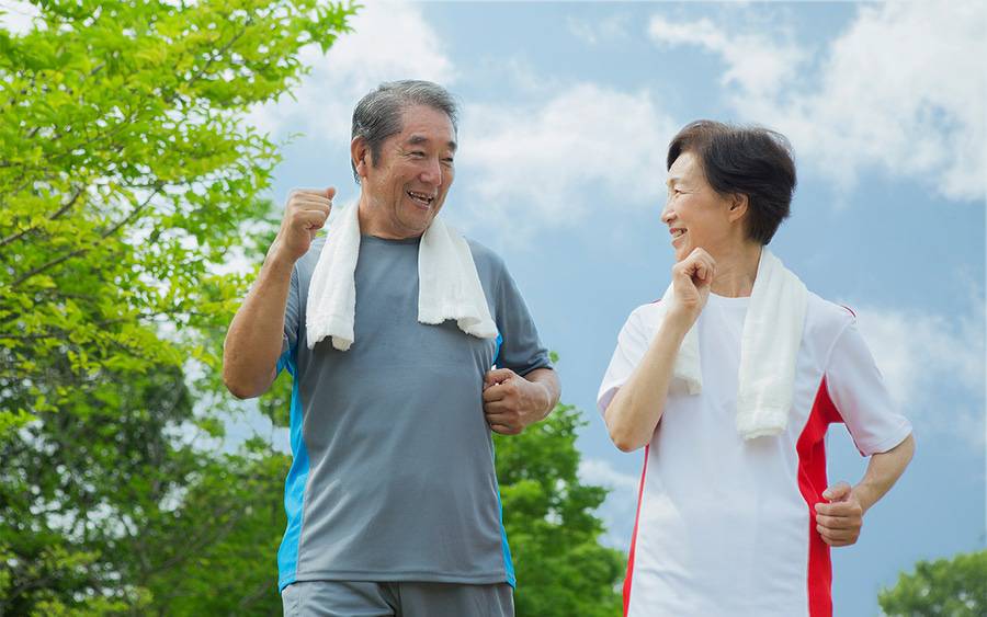 An older Asian-American couple exercise during day to help lower their risk of cancer.