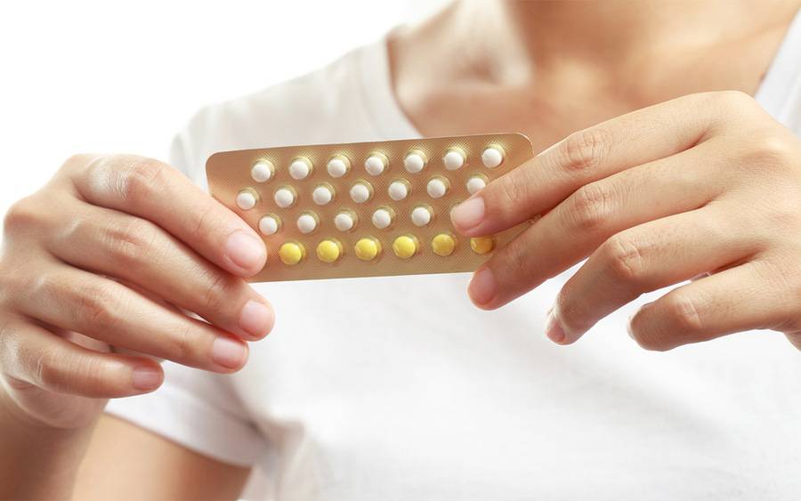 A woman holding birth control pills, which can be used for treatment for acne.