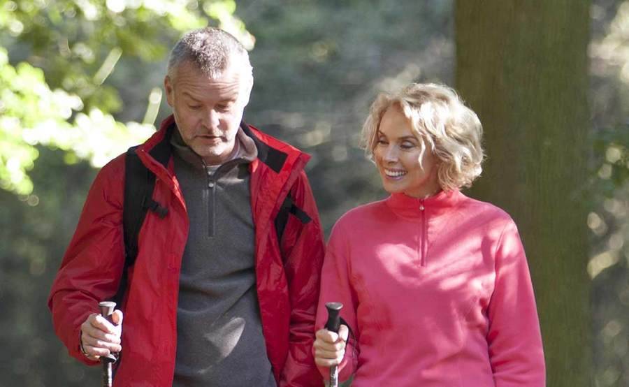 A smiling mature Caucasian couple hiking represent the full life that can be led after treatment for brain cancer or central nervous system tumors.