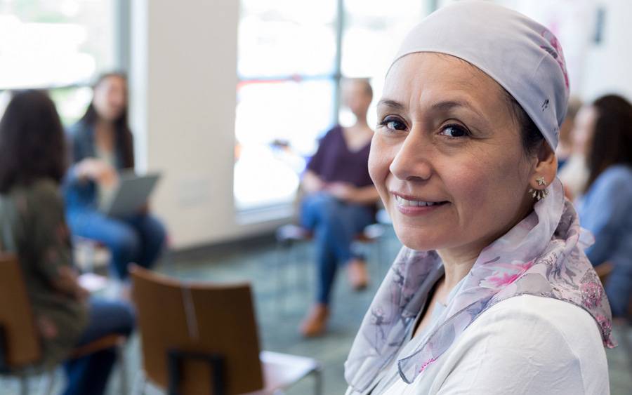 A breast cancer patient smiles as she meets with others for emotional support and share experiences along her cancer journey.