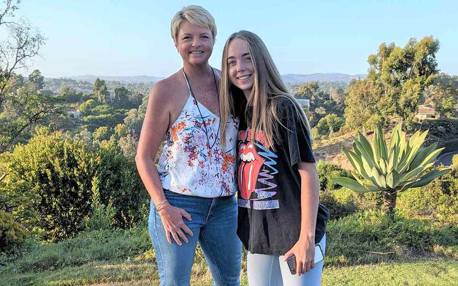 Breast cancer survivor, Carrie Steele, smiles with her daughter outdoors and is happy to give back to others with cancer.
