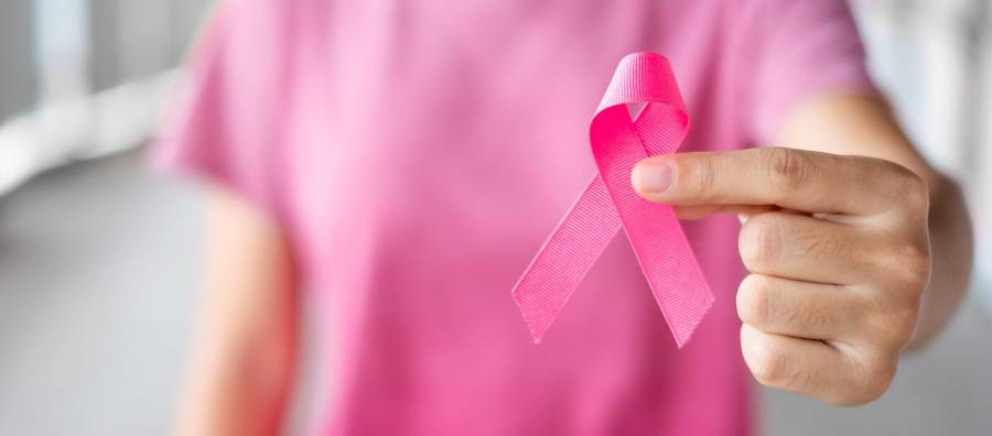 A woman holds up a pink ribbon that symbolizes breast cancer awareness.