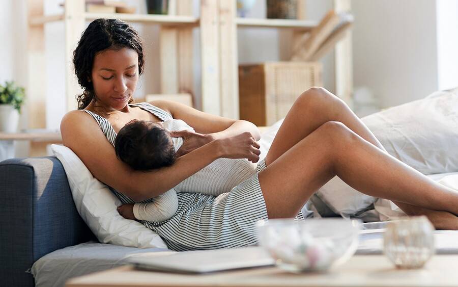 An African-American mother breastfeeding her baby during COVID-19 pandemic.