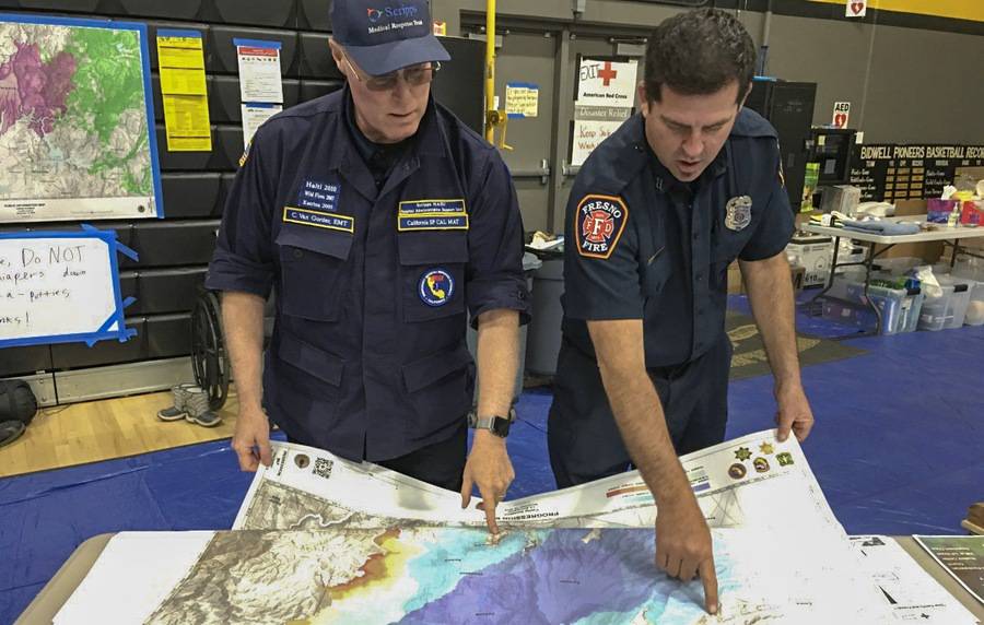 Scripps CEO, Chris Van Gorder, and a fireman review a fire map while feeling grateful to work together on fire relief plans.