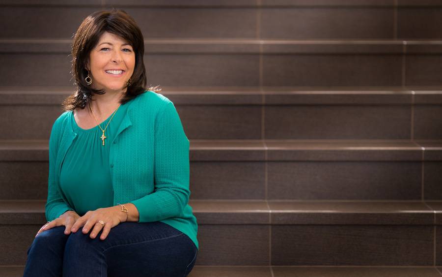 Susan Millsom, a Scripps MD Anderson cancer patient, sits on a set of stairs and is proud of her cancer treatment progress.