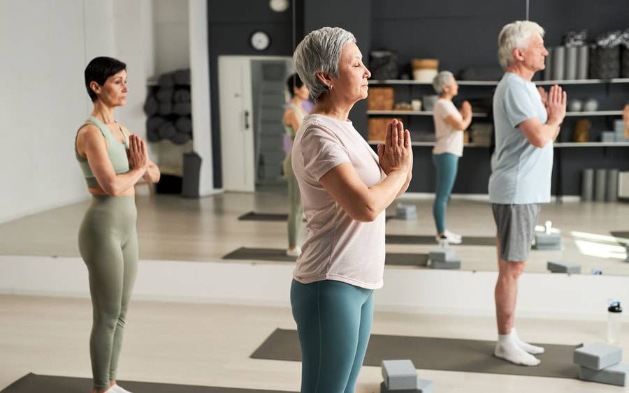 Men and women participate in a  restorative yoga class learning simple stretches and poses that focuses on relaxation and rejuvenation.