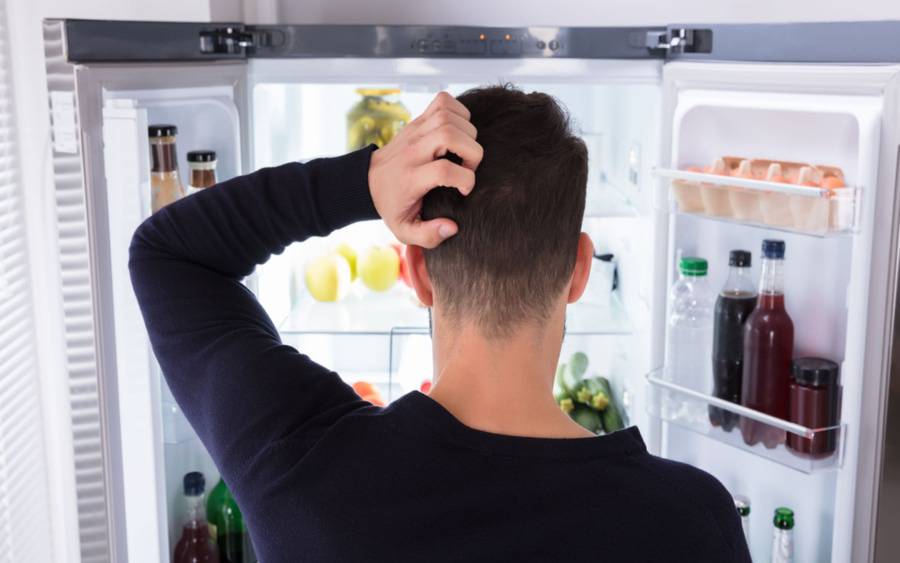 A cancer patient who is watching his diet checks for food options in his refrigerator.