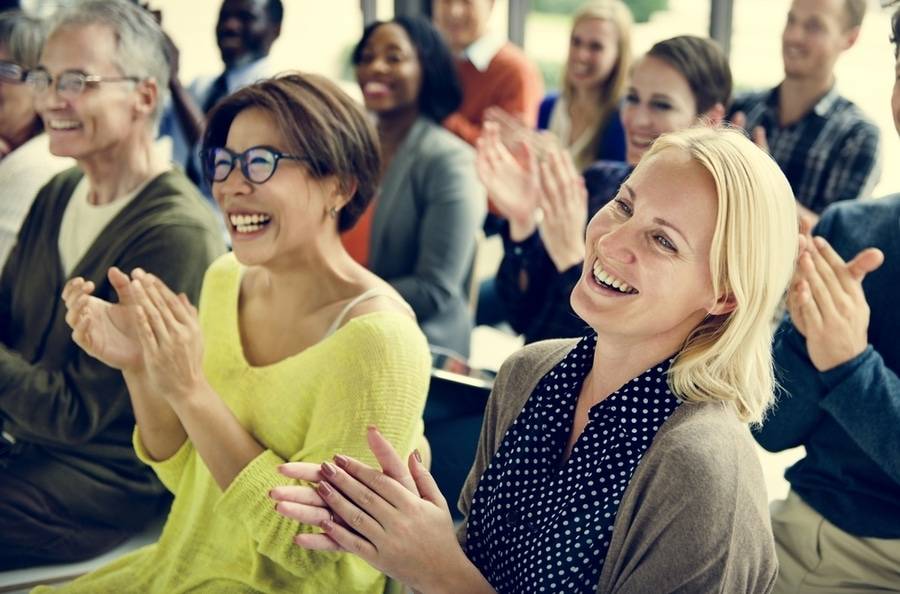 Two mature women clap their hands at a Cancer Survivors Day event.