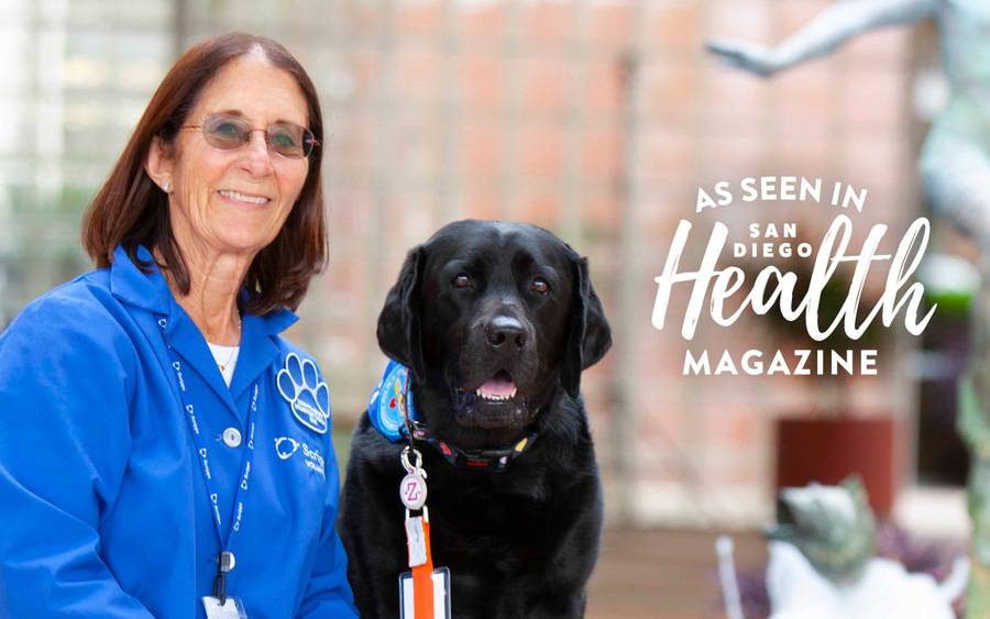 A canine therapy volunteer and her dog smile outside the hospital. San Diego Health Magazine