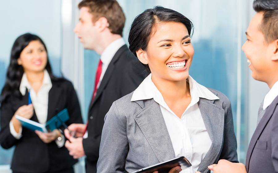 Woman in suit smiling and speaking with man