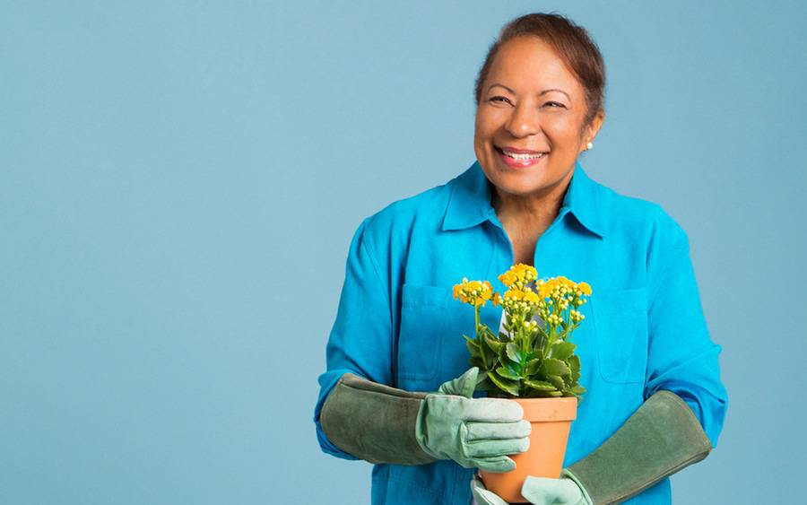 Carolyn Honore, a Scripps MD Anderson cancer patient, smiles as she holds a pot of yellow flowers after surviving cancer.