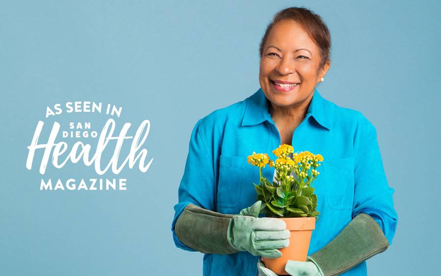 Carolyn Honore wears gardening gloves and holds a small plant in a terra cotta pot after her cancer treatment at Scripps.
